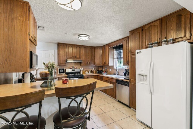 2041 Mill Creek Rd, Jacksonville, FL 32211 - kitchen with appliances with stainless steel finishes, under cabinet range hood, a sink, light countertops, and light tile patterned flooring