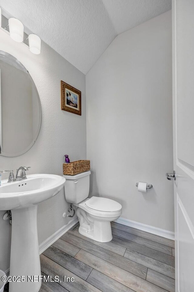 4604 Clapboard Crossing Way, Jacksonville, FL 32226 - bathroom featuring toilet, vaulted ceiling, a textured ceiling, wood finish floors, and baseboards