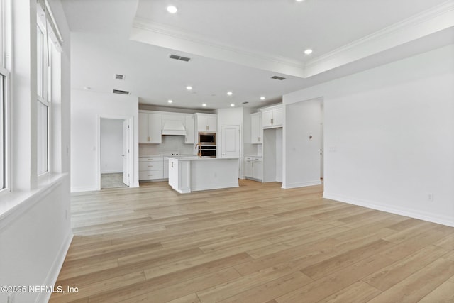 2446 Glade Ln, Green Cove Springs, FL 32043 - unfurnished living room featuring a raised ceiling, crown molding, light wood-type flooring, recessed lighting, and baseboards