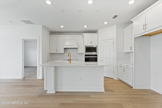 2446 Glade Ln, Green Cove Springs, FL 32043 - kitchen featuring oven, stainless steel microwave, decorative backsplash, light countertops, and a kitchen island with sink