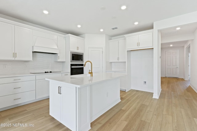 2446 Glade Ln, Green Cove Springs, FL 32043 - kitchen with custom range hood, black appliances, white cabinets, backsplash, and light countertops