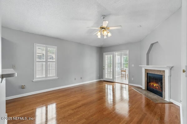 4420 Timber Hollow Way, Jacksonville, FL 32224 - unfurnished living room with ceiling fan, a glass covered fireplace, wood finished floors, baseboards, and a textured ceiling