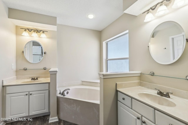 1346 N Kyle Way, Jacksonville, FL 32259 - bathroom featuring two vanities, a garden tub, a textured ceiling, and wood finished floors