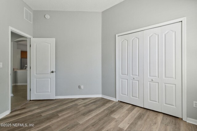 3353 Horseshoe Trail Dr, Orange Park, FL 32065 - unfurnished bedroom featuring wood finished floors, a closet, baseboards, arched walkways, and stainless steel fridge with ice dispenser