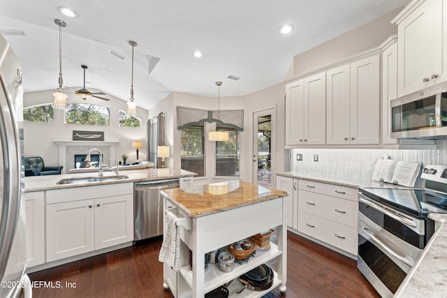 1758 Country Walk Dr, Fleming Island, FL 32003 - kitchen with stainless steel appliances, a ceiling fan, white cabinets, open floor plan, and a glass covered fireplace