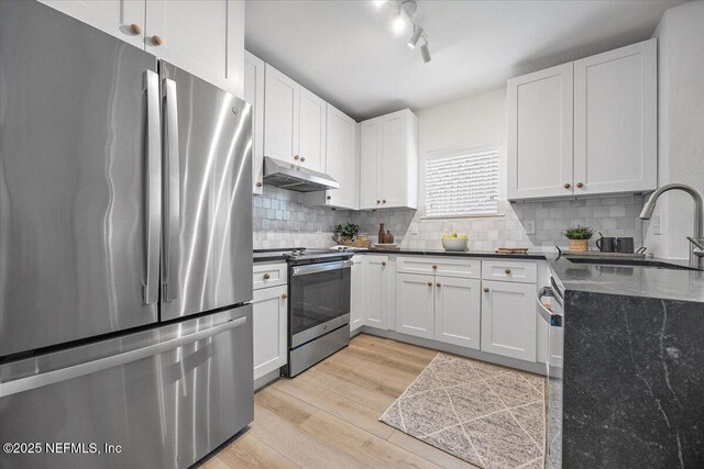 1800 The Greens Way Unit 1907, Jacksonville Beach, FL 32250 - kitchen featuring stainless steel appliances, under cabinet range hood, a sink, light wood-style floors, and white cabinetry