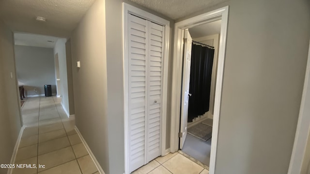 5923 Green Hill Ln, Jacksonville, FL 32211 - hallway featuring light tile patterned flooring, a textured ceiling, and baseboards
