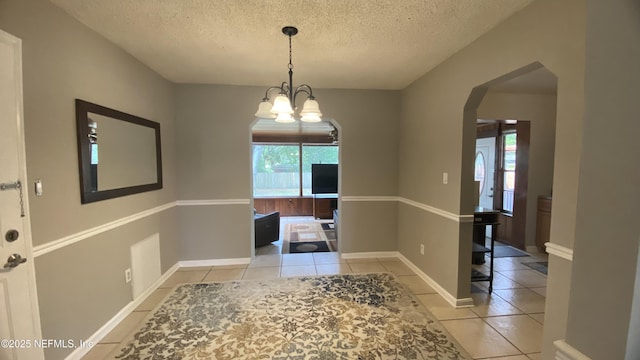 5923 Green Hill Ln, Jacksonville, FL 32211 - unfurnished dining area with arched walkways, tile patterned floors, a textured ceiling, a chandelier, and baseboards