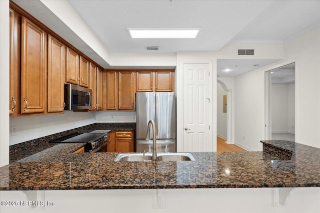 150 Pantano Cay Blvd Unit 2303, Saint Augustine, FL 32080 - kitchen with appliances with stainless steel finishes, dark stone countertops, brown cabinetry, a peninsula, and arched walkways