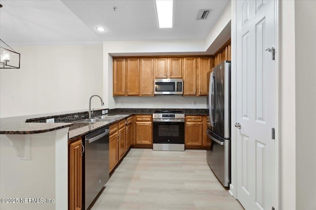 150 Pantano Cay Blvd Unit 2303, Saint Augustine, FL 32080 - kitchen with appliances with stainless steel finishes, light wood-style flooring, brown cabinets, dark stone counters, and a peninsula