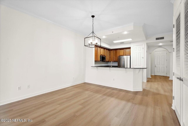 150 Pantano Cay Blvd Unit 2303, Saint Augustine, FL 32080 - kitchen featuring appliances with stainless steel finishes, a peninsula, light wood-style floors, brown cabinetry, and ornamental molding