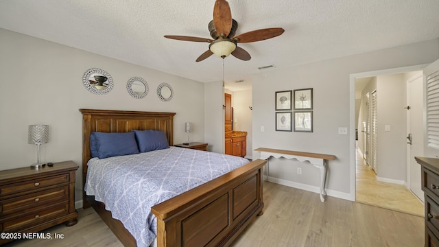 87 Village Del Lago Cir, Saint Augustine, FL 32080 - bedroom with light wood-style floors, a textured ceiling, a ceiling fan, baseboards, and connected bathroom