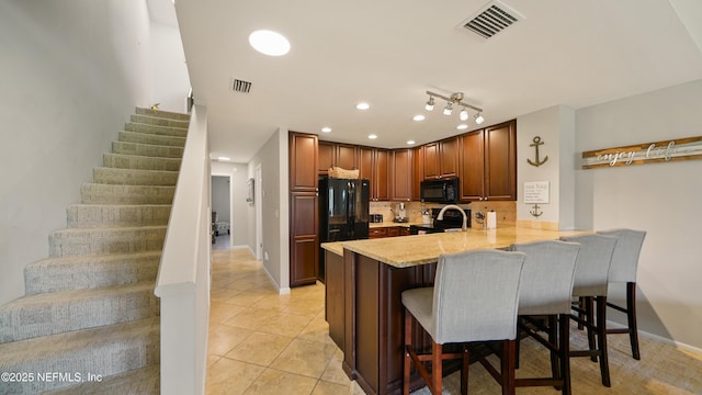 87 Village Del Lago Cir, Saint Augustine, FL 32080 - kitchen featuring black appliances, a peninsula, light countertops, a breakfast bar, and light tile patterned floors