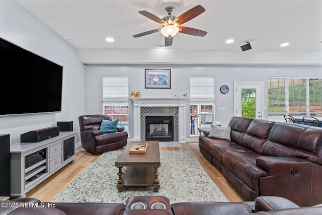 1321 Honeysuckle Dr, Saint Johns, FL 32259 - living room featuring light wood-type flooring, a ceiling fan, a tiled fireplace, a textured ceiling, and recessed lighting
