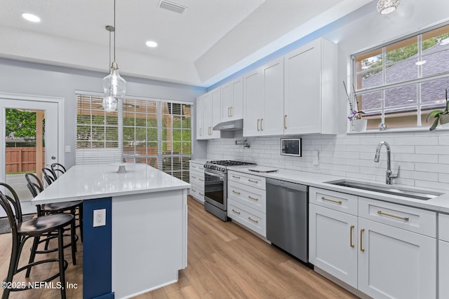 1321 Honeysuckle Dr, Saint Johns, FL 32259 - kitchen with appliances with stainless steel finishes, a sink, under cabinet range hood, a breakfast bar, and decorative backsplash