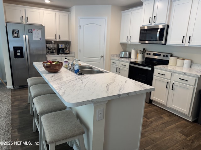 126 Falcon Ridge Rd, Saint Augustine, FL 32084 - kitchen with stainless steel appliances, dark wood-style flooring, white cabinets, a kitchen island with sink, and a breakfast bar area