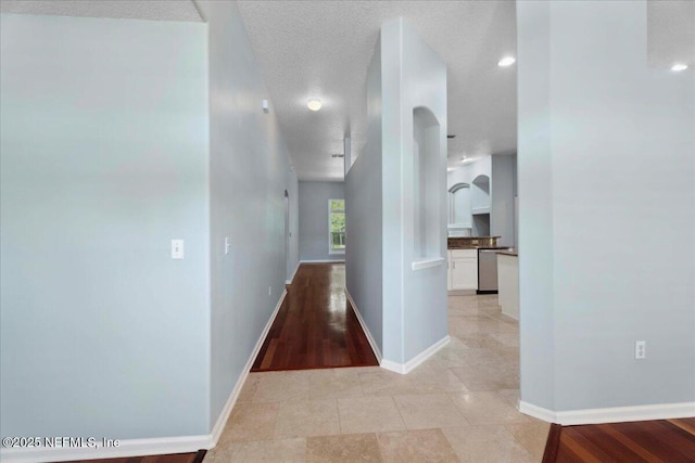 8681 Canopy Oaks Dr, Jacksonville, FL 32256 - hallway featuring arched walkways, baseboards, light tile patterned floors, and a textured ceiling