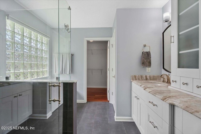 8681 Canopy Oaks Dr, Jacksonville, FL 32256 - bathroom featuring vanity, baseboards, a shower with door, and a walk in closet