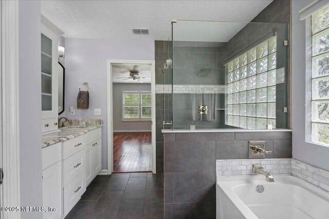 8681 Canopy Oaks Dr, Jacksonville, FL 32256 - bathroom featuring a ceiling fan, a bath, vanity, tile patterned floors, and a tile shower