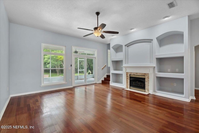 8681 Canopy Oaks Dr, Jacksonville, FL 32256 - unfurnished living room featuring baseboards, a textured ceiling, built in features, ceiling fan, and hardwood / wood-style flooring