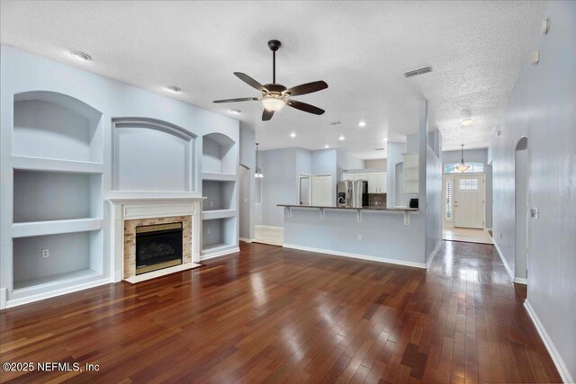8681 Canopy Oaks Dr, Jacksonville, FL 32256 - unfurnished living room with baseboards, a ceiling fan, built in features, dark wood finished floors, and a textured ceiling