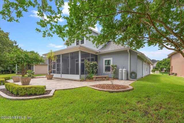 8681 Canopy Oaks Dr, Jacksonville, FL 32256 - rear view of house featuring a sunroom, a patio, a lawn, and stucco siding