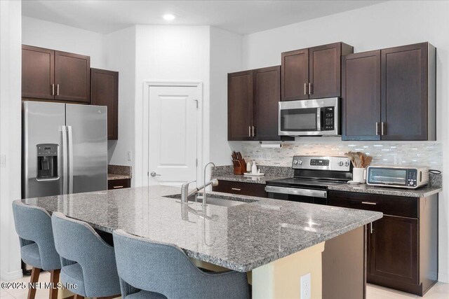 1976 Red Loop, Lakeland, FL 33801 - kitchen with stainless steel appliances, a breakfast bar area, a sink, stone countertops, and recessed lighting