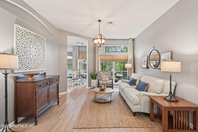 1823 Sentry Oak Ct, Fleming Island, FL 32003 - living room featuring light wood-style floors, a chandelier, arched walkways, and baseboards
