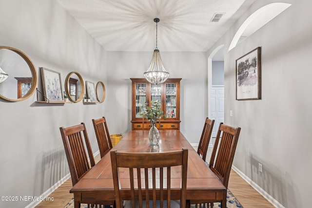 1823 Sentry Oak Ct, Fleming Island, FL 32003 - dining space with arched walkways, wood finished floors, a chandelier, and baseboards