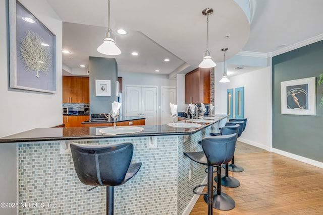 1925 S Atlantic Ave Unit 1005, Daytona Beach Shores, FL 32118 - kitchen featuring dark countertops, brown cabinetry, light wood-type flooring, a kitchen breakfast bar, and recessed lighting