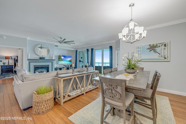 1925 S Atlantic Ave Unit 1005, Daytona Beach Shores, FL 32118 - dining area with a chandelier, crown molding, wood finished floors, ceiling fan, and a glass covered fireplace