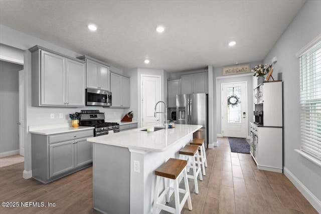 46 Killarney Ave, Saint Johns, FL 32259 - kitchen with stainless steel appliances, gray cabinets, a sink, wood finished floors, and a kitchen bar