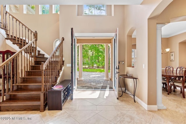69 Bridle Ridge Ct, Flagler Beach, FL 32136 - tiled foyer entrance with stairs, ornate columns, a high ceiling, arched walkways, and baseboards