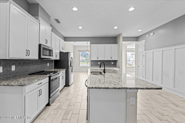 27 Shady Lake Ct, Saint Augustine, FL 32095 - kitchen with appliances with stainless steel finishes, a sink, decorative backsplash, white cabinets, and a textured ceiling