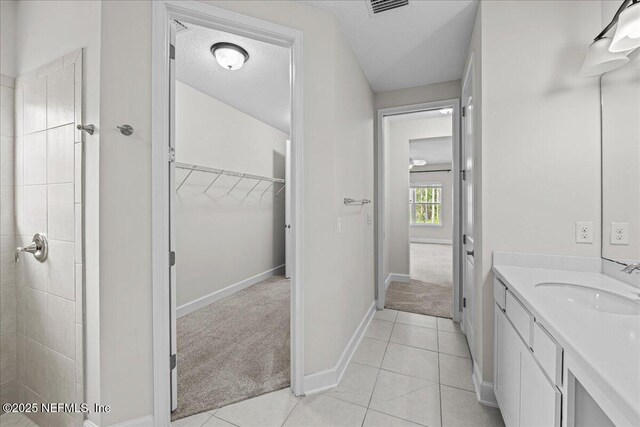 27 Shady Lake Ct, Saint Augustine, FL 32095 - full bathroom featuring vanity, baseboards, a spacious closet, tile patterned flooring, and tiled shower
