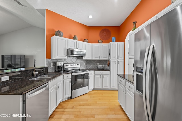 4340 Comanche Trail Blvd, Saint Johns, FL 32259 - kitchen with appliances with stainless steel finishes, light wood-type flooring, white cabinets, decorative backsplash, and dark stone counters