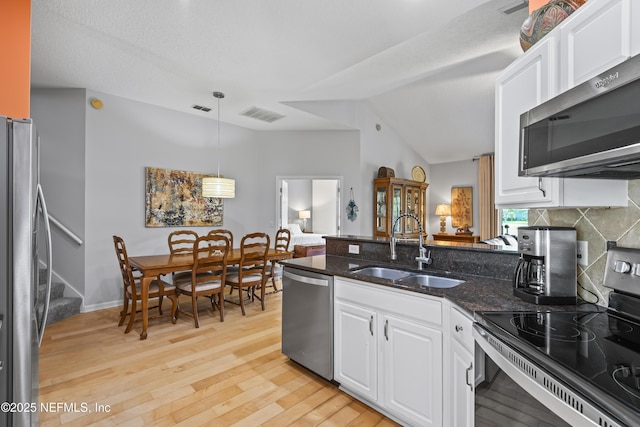 4340 Comanche Trail Blvd, Saint Johns, FL 32259 - kitchen featuring appliances with stainless steel finishes, a peninsula, white cabinetry, dark stone counters, and lofted ceiling