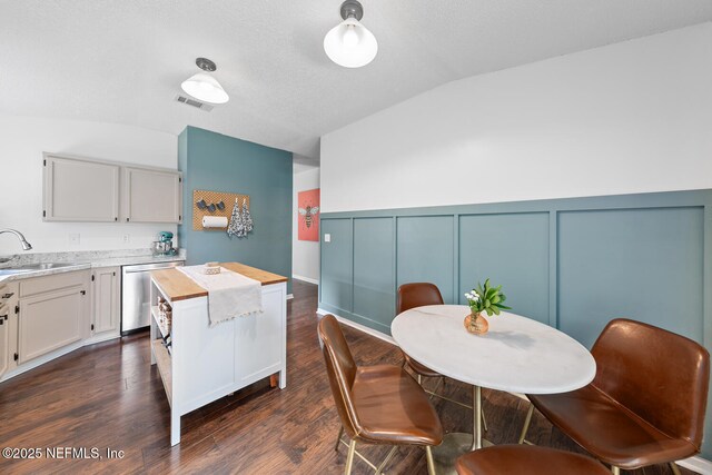 1501 Cove Landing Dr, Jacksonville, FL 32233 - dining room featuring vaulted ceiling, a decorative wall, dark wood-type flooring, and wainscoting