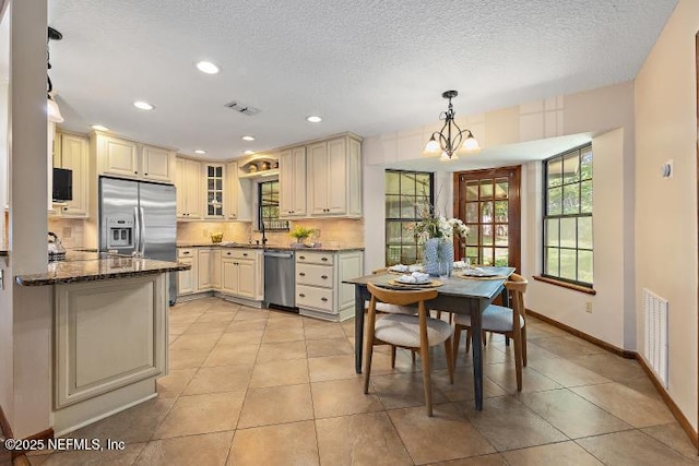 2768 N Periwinkle Ave, Middleburg, FL 32068 - kitchen featuring appliances with stainless steel finishes, cream cabinets, a chandelier, baseboards, and light tile patterned floors