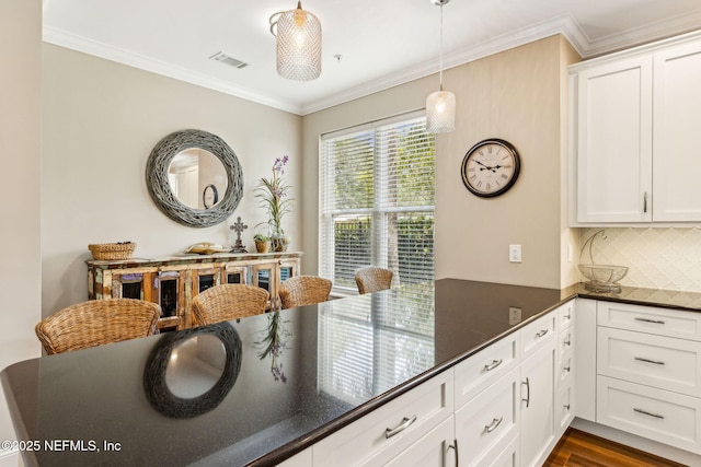 1899 White Sands Way Unit 704, Fernandina Beach, FL 32034 - kitchen featuring decorative backsplash, crown molding, white cabinets, decorative light fixtures, and dark wood-style flooring