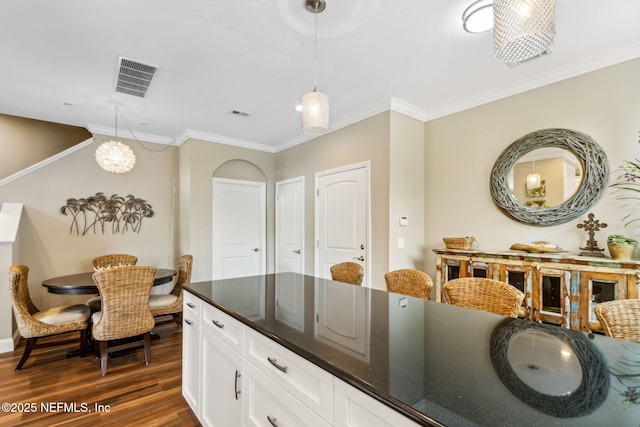 1899 White Sands Way Unit 704, Fernandina Beach, FL 32034 - kitchen with dark countertops, dark wood finished floors, crown molding, white cabinetry, and pendant lighting