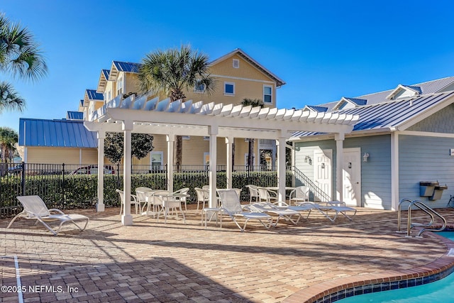 1899 White Sands Way Unit 704, Fernandina Beach, FL 32034 - back of house featuring a pergola, a standing seam roof, a patio area, metal roof, and a community pool