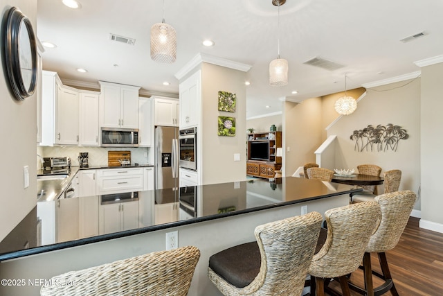 1899 White Sands Way Unit 704, Fernandina Beach, FL 32034 - kitchen with appliances with stainless steel finishes, crown molding, dark countertops, backsplash, and a peninsula