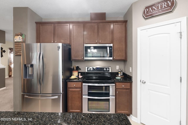 203 Buck Run Way, Saint Augustine, FL 32092 - kitchen with stainless steel appliances, dark stone counters, and brown cabinets