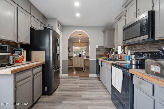 1942 Calusa Trl, Middleburg, FL 32068 - kitchen with appliances with stainless steel finishes, gray cabinets, decorative backsplash, a sink, and arched walkways
