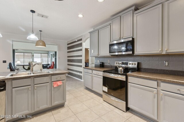 3592 Harrier Ct, Middleburg, FL 32068 - kitchen with appliances with stainless steel finishes, gray cabinetry, ornamental molding, arched walkways, and hanging light fixtures