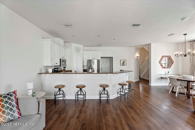 28 S Comares Ave, Saint Augustine Beach, FL 32080 - kitchen featuring appliances with stainless steel finishes, white cabinetry, dark wood-style flooring, a kitchen breakfast bar, and a textured ceiling