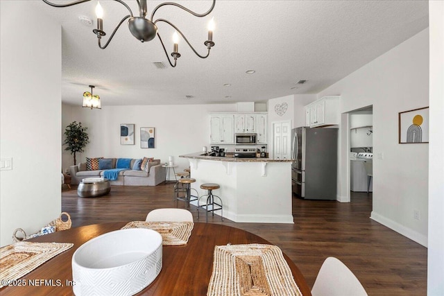 28 S Comares Ave, Saint Augustine Beach, FL 32080 - living area with a chandelier, dark wood-type flooring, a textured ceiling, independent washer and dryer, and baseboards