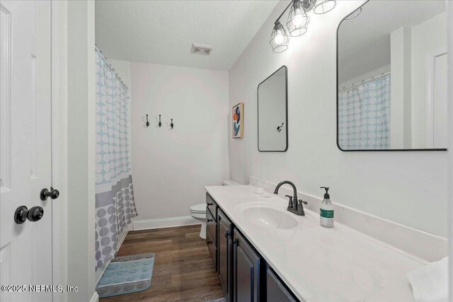 28 S Comares Ave, Saint Augustine Beach, FL 32080 - full bathroom featuring vanity, wood finished floors, toilet, a textured ceiling, and baseboards