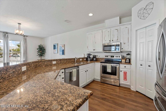 28 S Comares Ave, Saint Augustine Beach, FL 32080 - kitchen with appliances with stainless steel finishes, white cabinetry, a sink, dark stone counters, and a textured ceiling